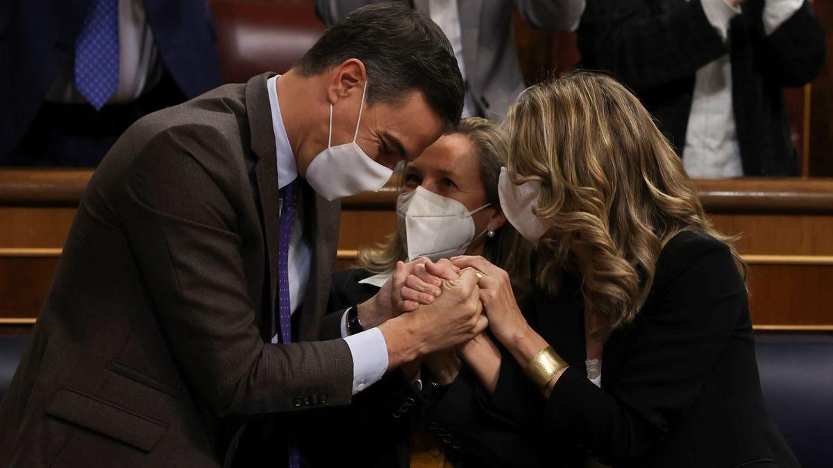 El presidente del Gobierno, Pedro Sánchez, la vicepresidenta primera, Nadia Calviño, y la vicepresidenta segunda, Yolanda Díaz, este jueves en el Congreso, se agarran tras conseguir aprobar la reforma laboral.