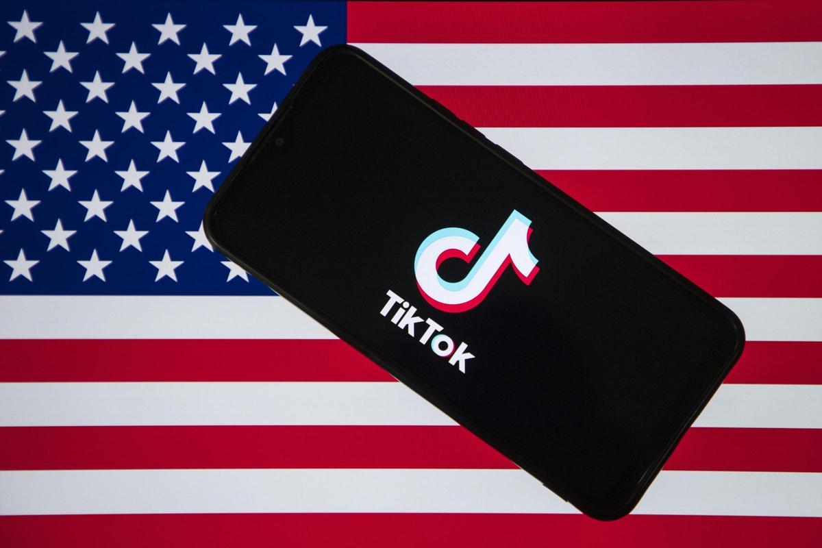 El logo de la plataforma TikTok bajo la bandera estadounidense.