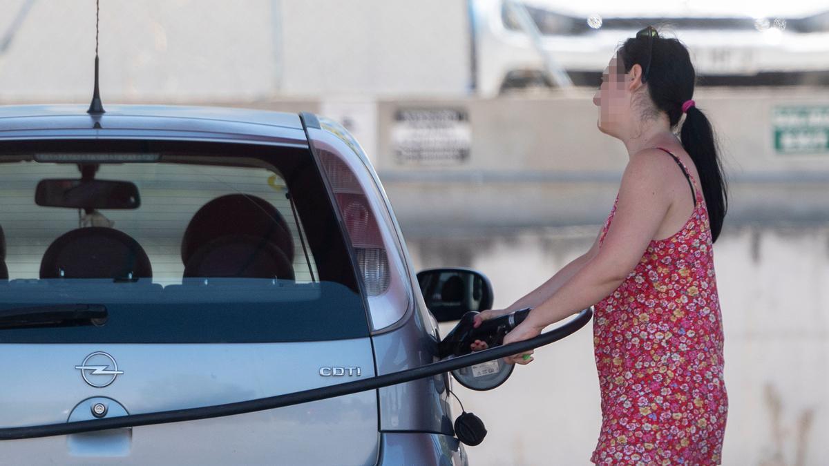 Una pasajera reposta en una gasolinera.