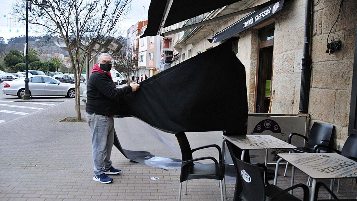 Un hostelero de Cangas recoge ayer su terraza en el centro. |  // G.N.