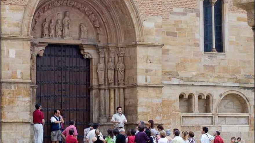 Varias personas, delante de la portada de la iglesia de San Juan del Mercado donde se observan las figuras