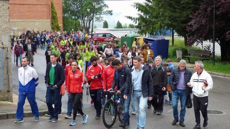 Verónica Pérez lleva la antorcha olímpica seguida de deportistas, escolares y vecinos de Tineo.