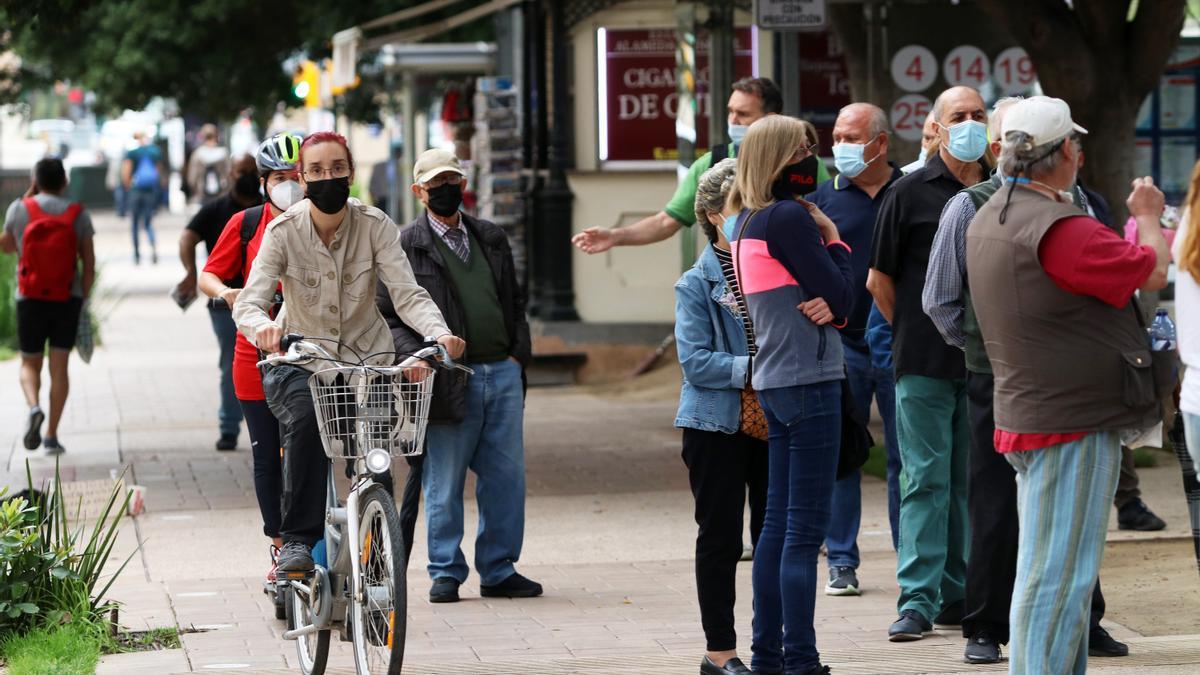 Una ciclista y un usuario de patinete pasan por el carril bici de la Alameda habilitado por el Ayuntamiento, con los usuarios del bus al lado.