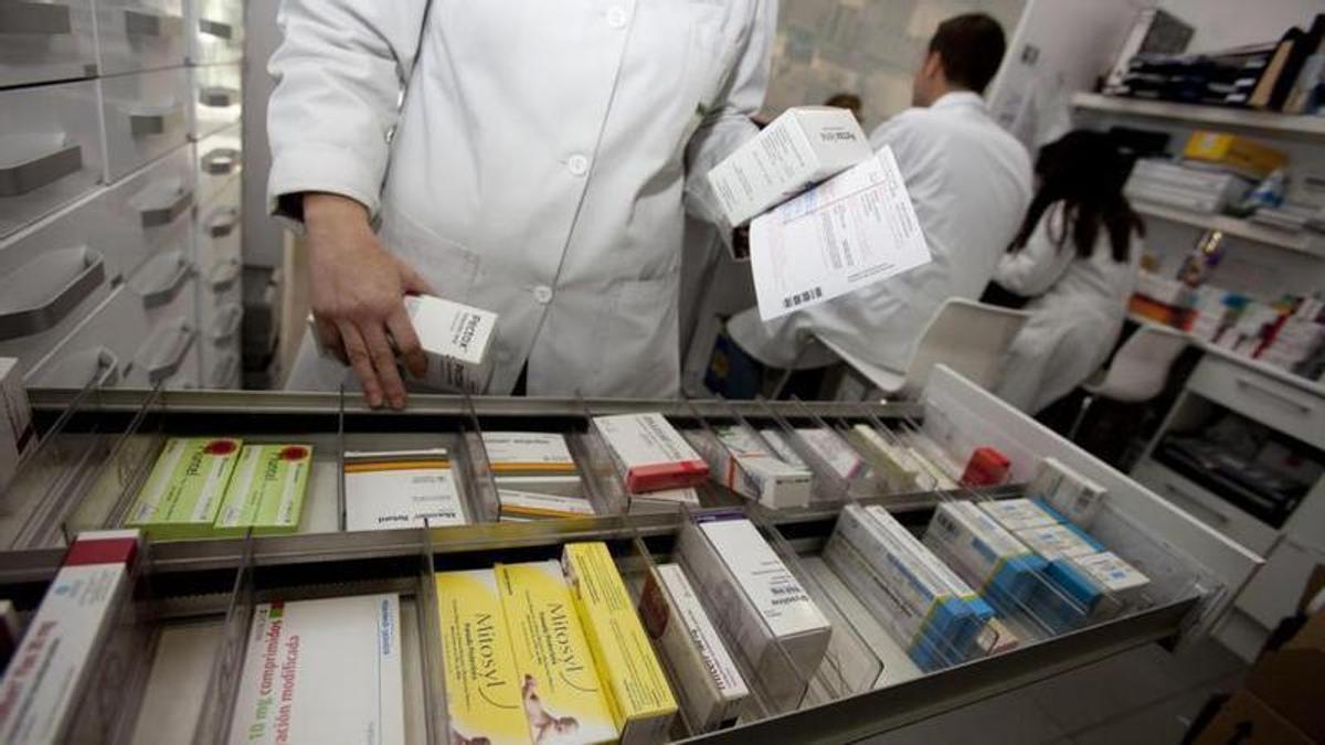 Un farmacéutico coge los medicamentos recetados a un paciente.