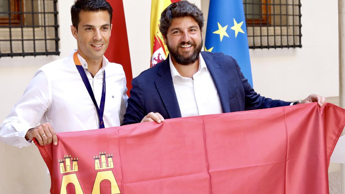 Miguel Ángel López Nicolás posa con una bandera de la Comunidad Autónoma con Fernando López Miras