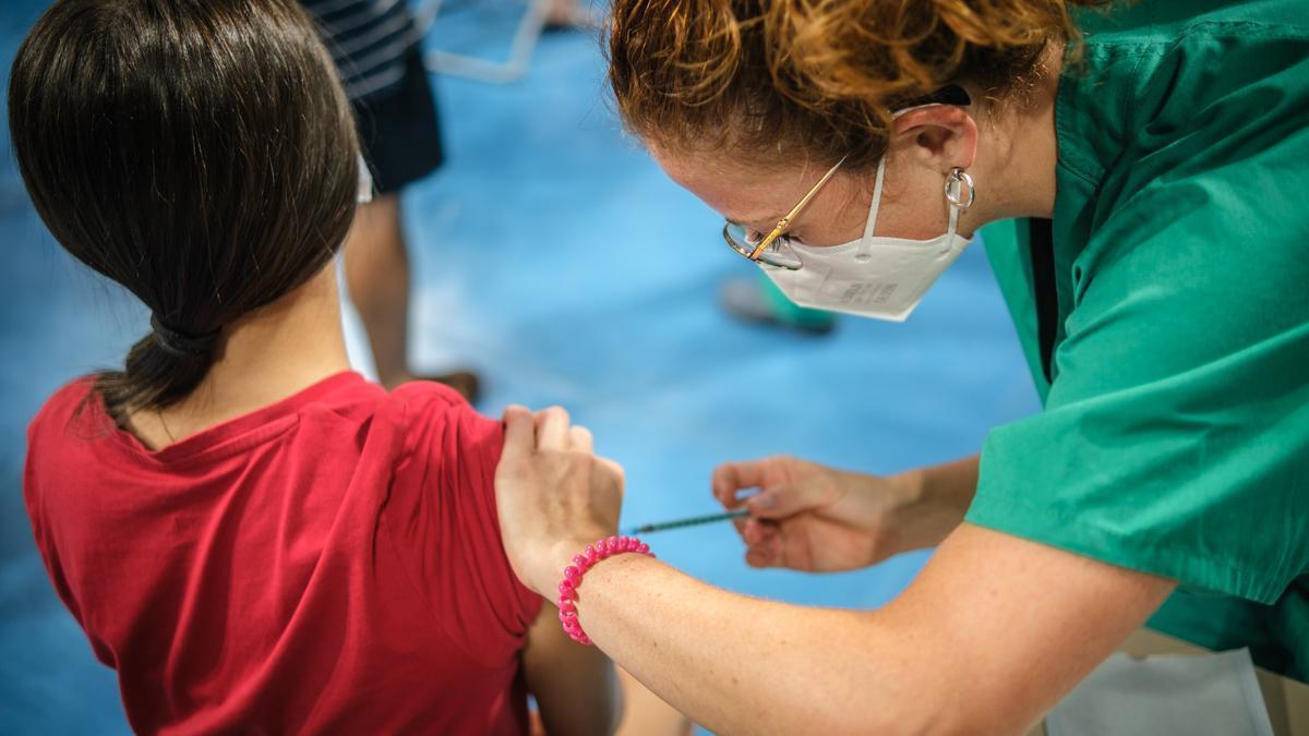Una sanitaria administra una vacuna a una niña.