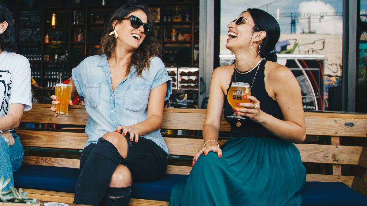 Dos amigas toman cerveza en la terraza de un bar