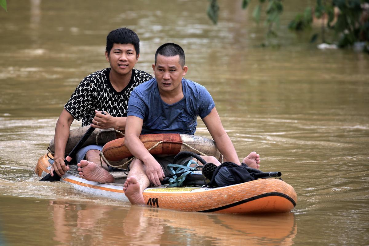 Dos hombres se desplazan en un bote en medio de la inundación en una calle de Hanoi, el martes.