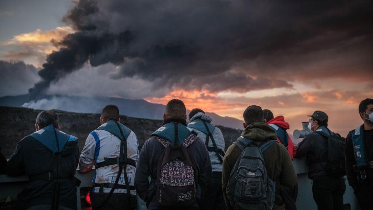 Un grupo de personas observan el volcán de Tajogaite.