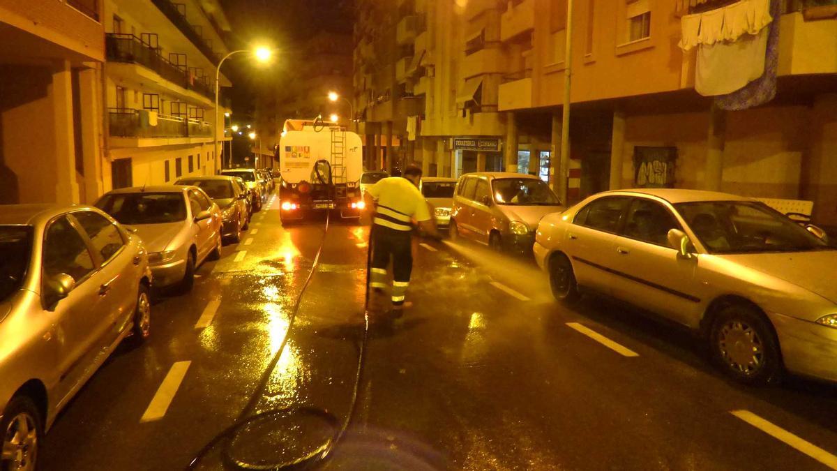 Un trabajador limpia una calle de Benidorm por la noche.