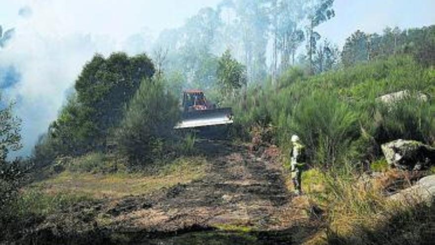 Un helicóptero descarga agua en el incendio de Augasantas.