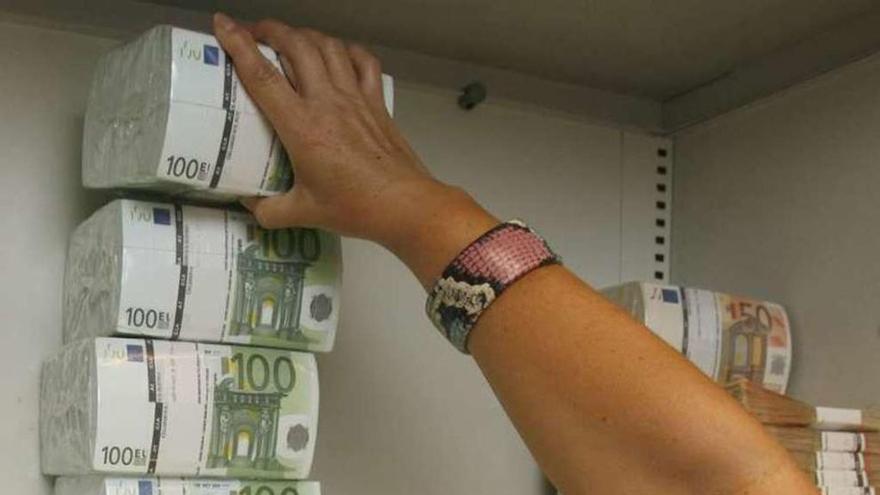 Una trabajadora de un banco guarda dinero en la caja fuerte.