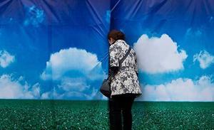 Una visitant espia a través d’un cartell amb escenografia col·locat com a tanca per tapar algunes obres de construcció a la plaça Tiananmen, a Pequín (Xina).