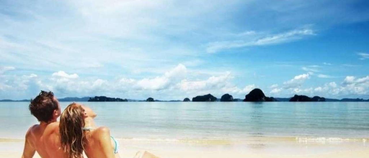 Una pareja, disfrutando del sol en una playa.