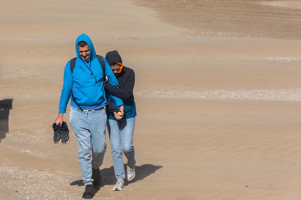 Una pareja se protege del viento en la playa de la Malva-rosa.