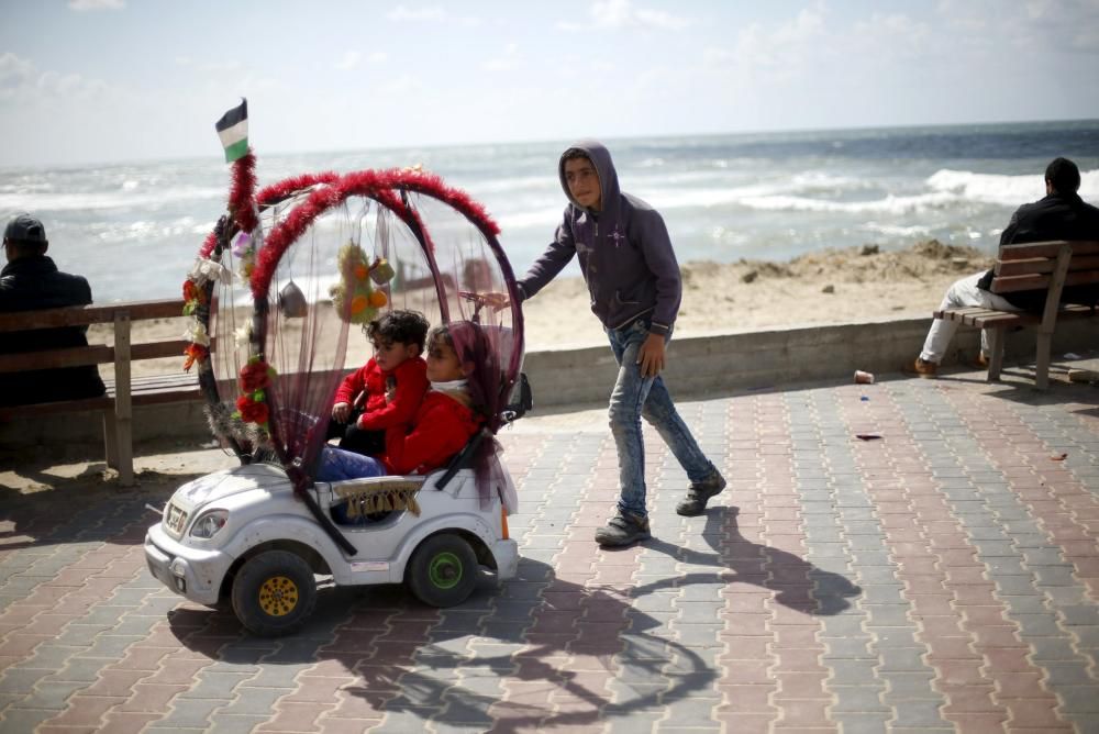 Mahand Salama, un niño palestino de 13 años, alquila su coche de juguete para que otros niños disfruten de un paseo por el puerto de la ciudad de Gaza.