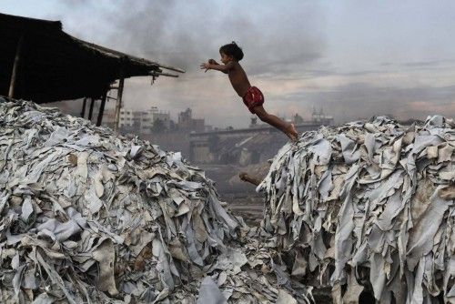 A child jumps on the waste products that are used to make poultry feed as she plays in a tannery at Hazaribagh in Dhaka