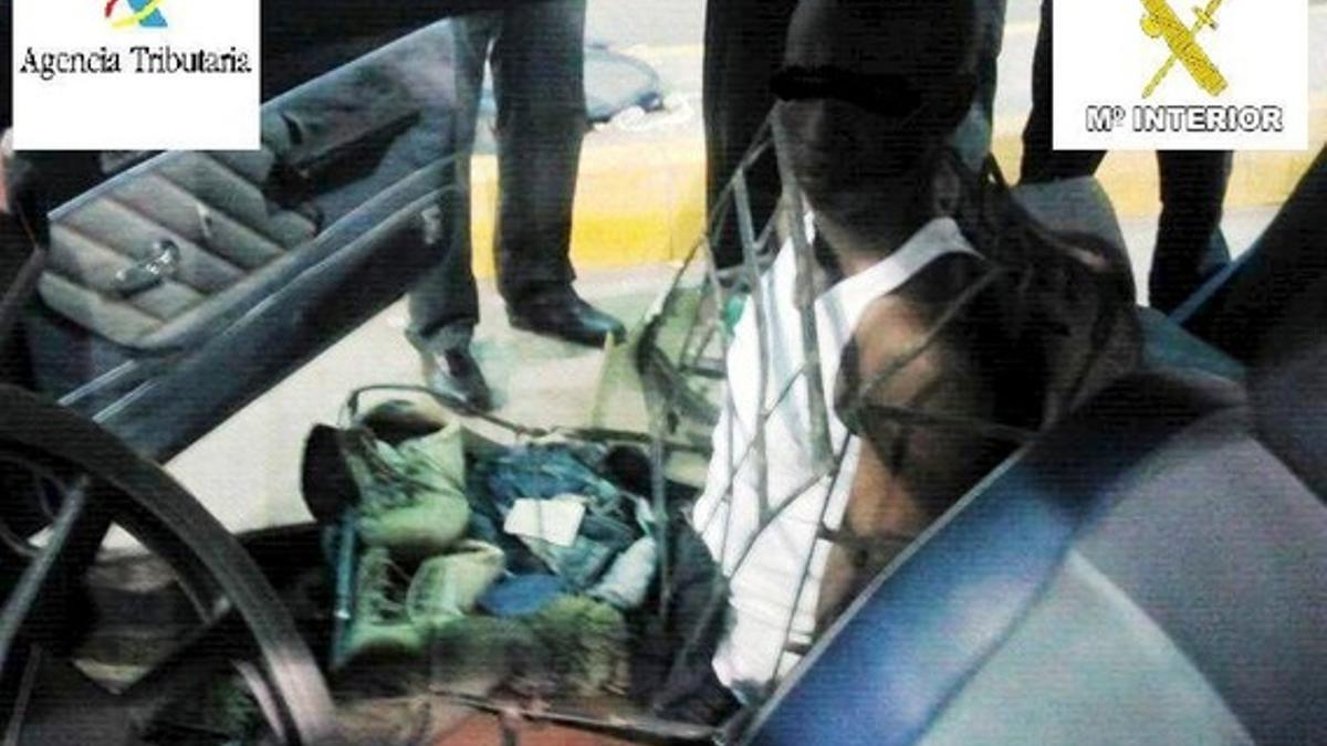 Imagen cedida por la Guardia Civil de Melilla de la detención del inmigrante camuflado como 'asiento' de coche.