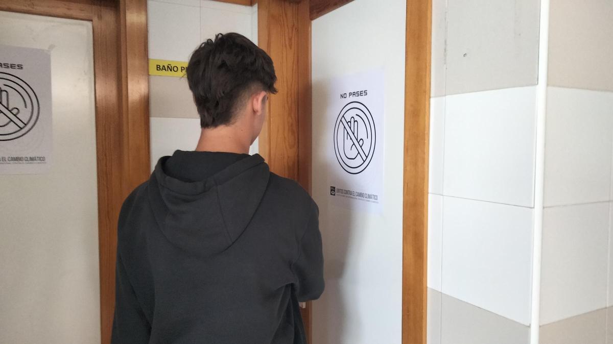 Las puertas de los baños con los carteles con el eslogan 'No pases... del cambio climático'.