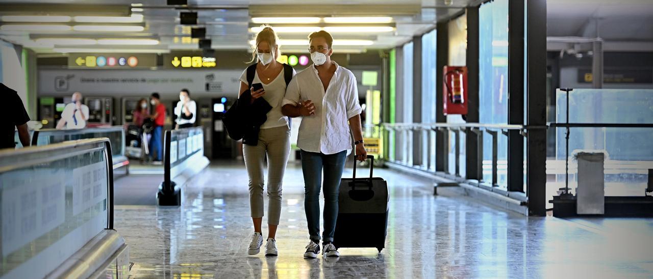 Una pareja de jóvenes, en un aeropuerto.