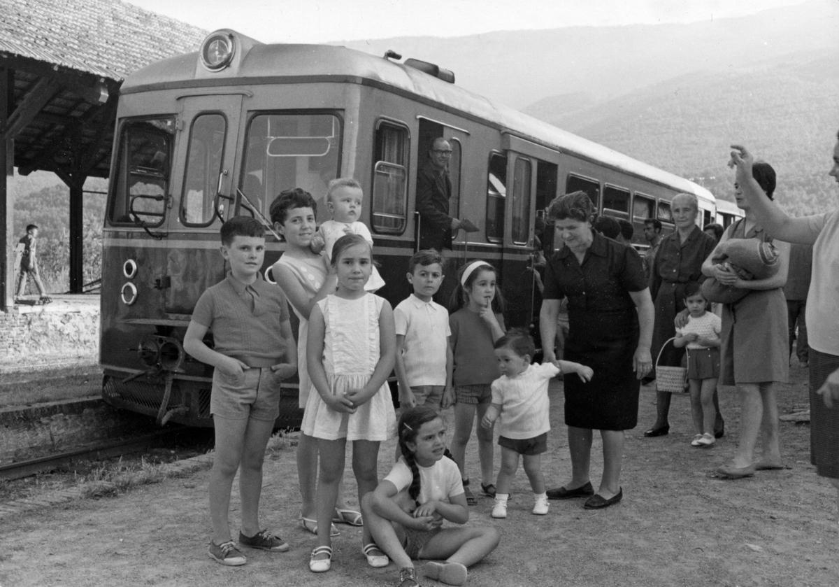 Mainada i famílies davant l'automotor al seu pas per les Planes d'Hostoles, l'any 1969.