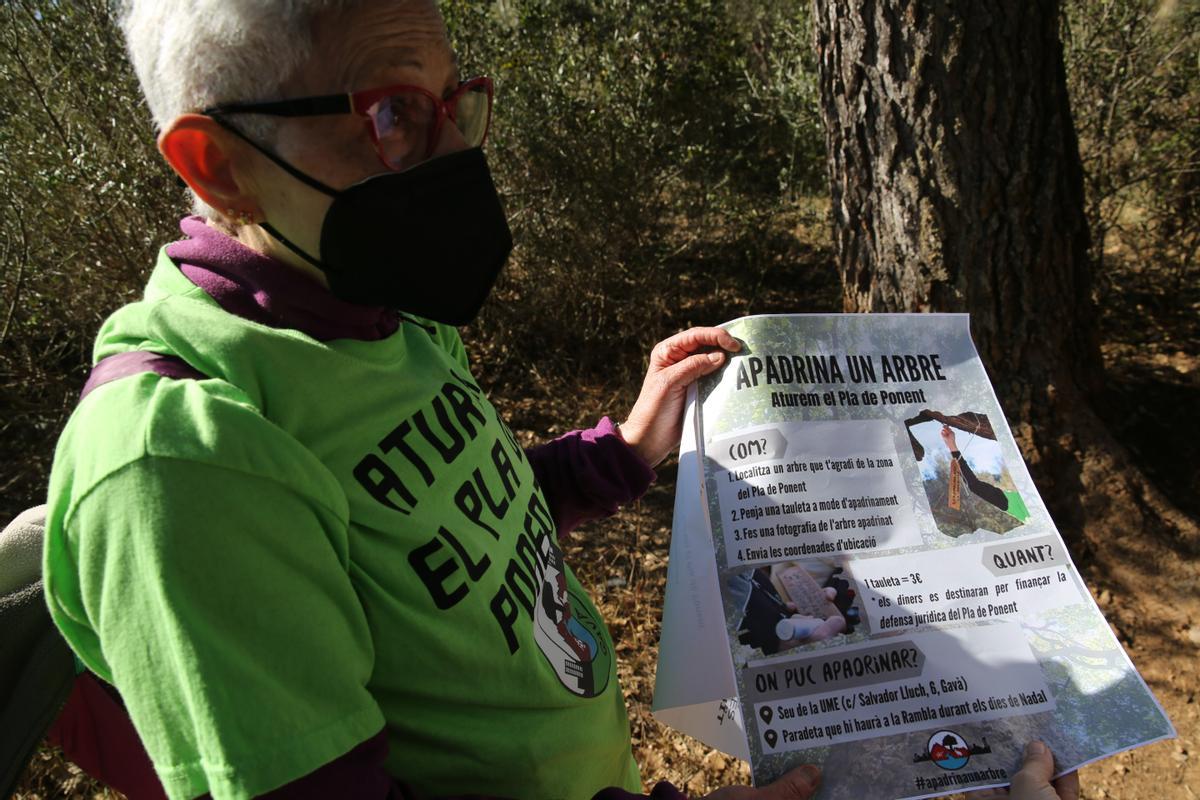Pilar Conte Gómez, activista vecinal de Gavà, muestra el cartel de la campaña Apadrina un árbol.