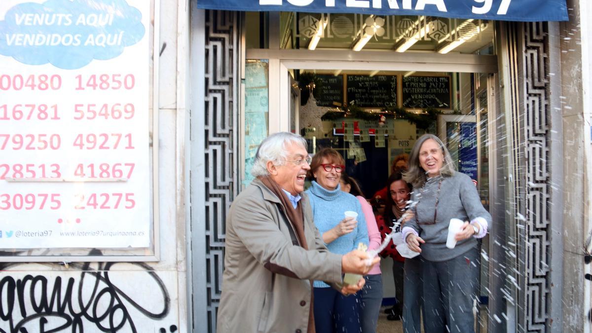 El dueño de la administración de lotería de la plaza Urquinaona, Pedro Fortuño, destapa una botella de cava por haber vendido un quinto premio de la lotería de Navidad.