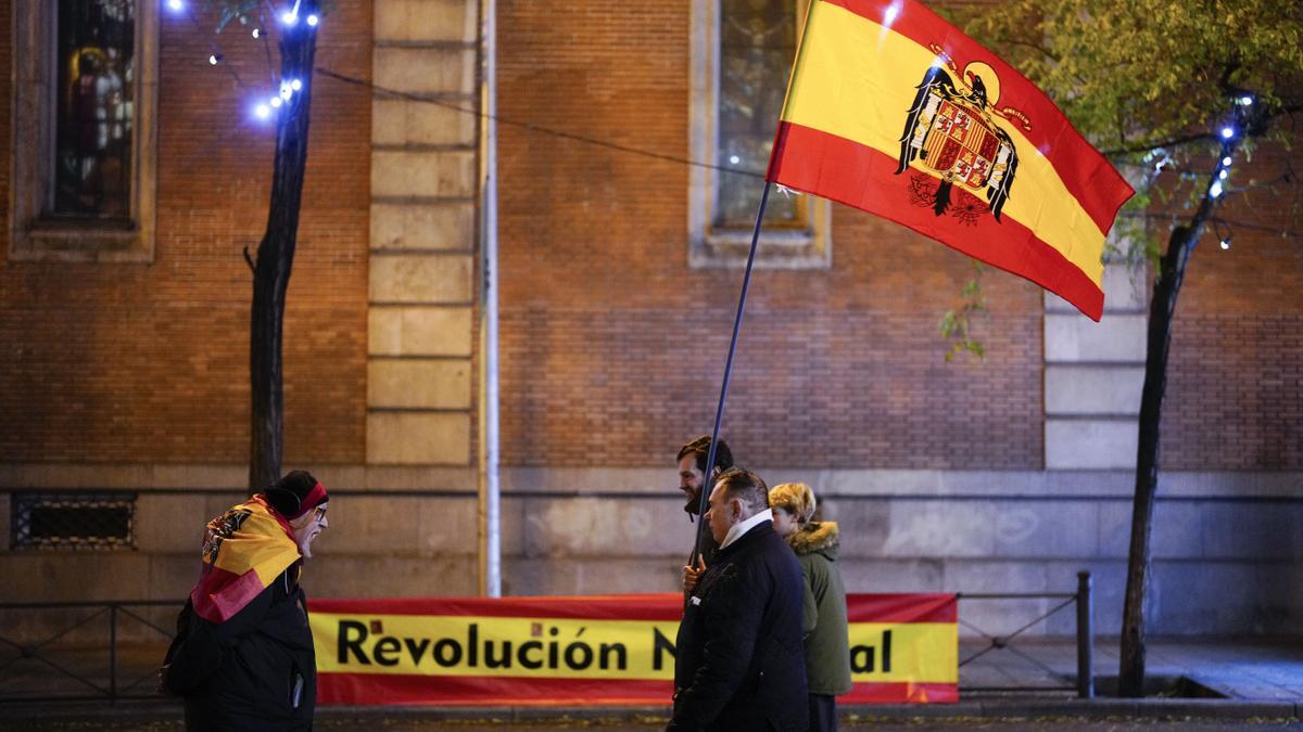 Protestantes 'constitucionalistas' contra la ley de amnistía portando una bandera preconstitucional cerca de la sede del PSOE en Ferraz (Madrid).