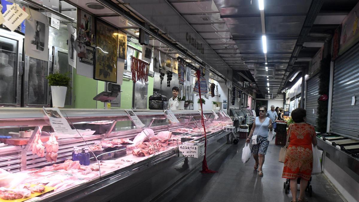 Personas pasan por delante del puesto de la carnicería de Paco Consuelo en la plaza de abastos de Verónicas en Murcia.