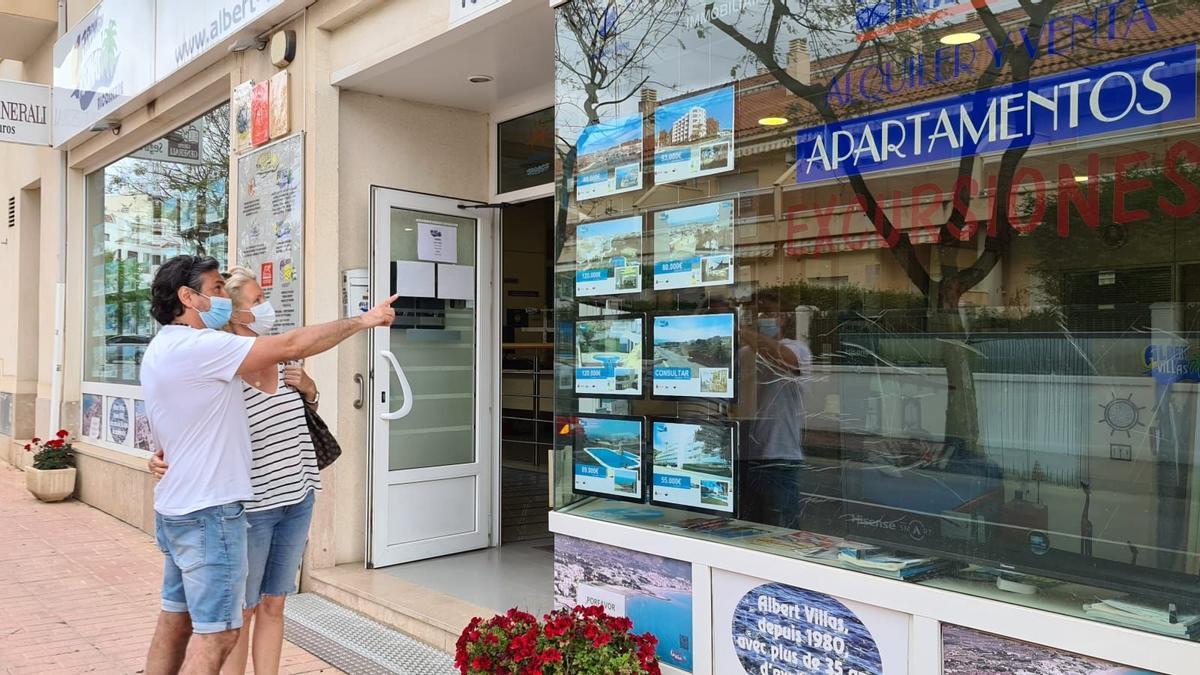 Una pareja consulta las opciones de apartamentos para alquilar este verano en el escaparate de una inmobiliaria ubicada en Alcossebre (archivo).