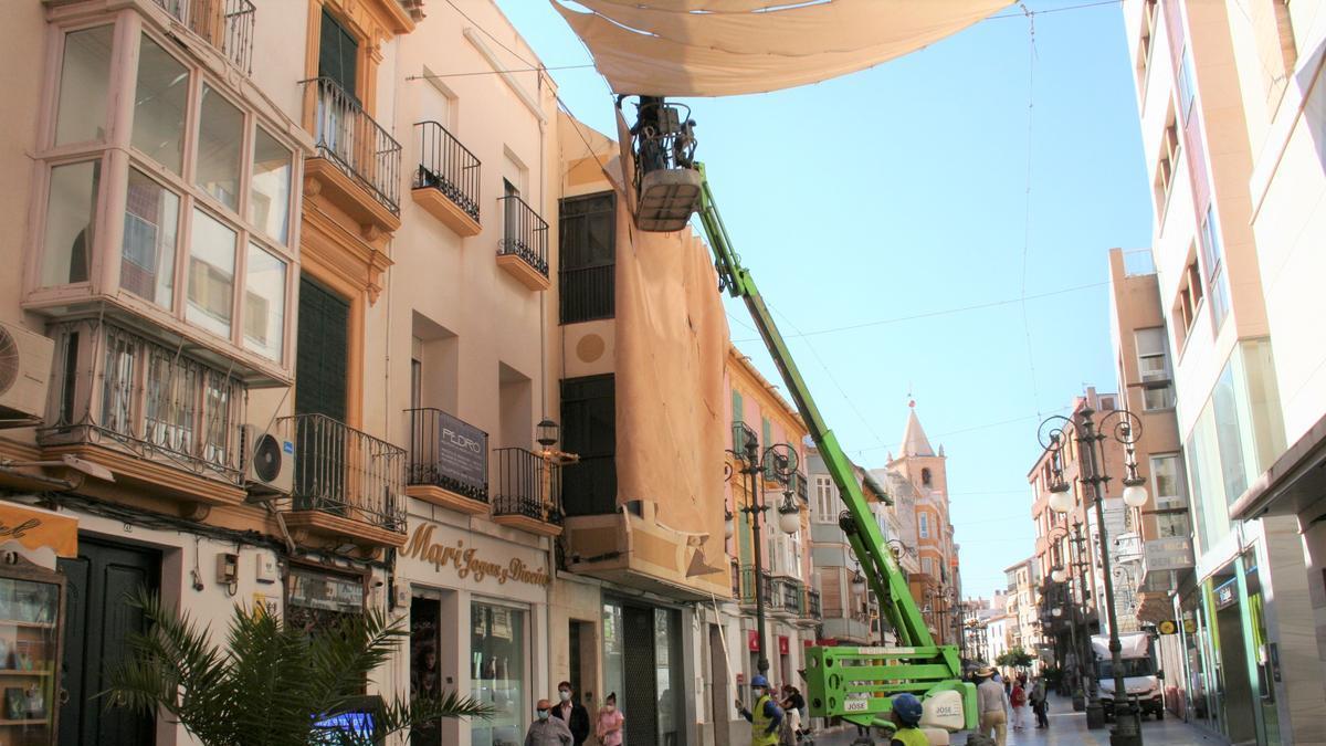 Operarios retirando los toldos de la calle Corredera.