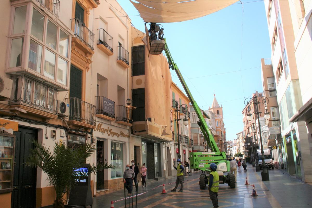 Operarios retirando los toldos de la calle Corredera.
