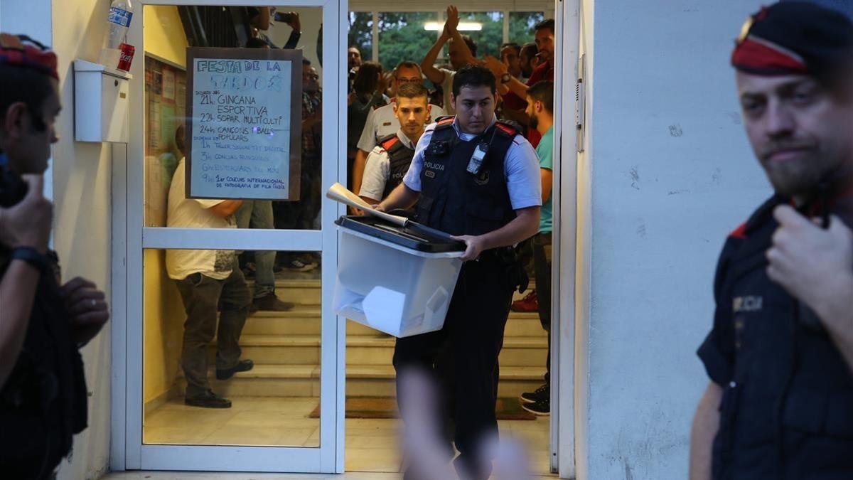 Un mosso se lleva una urna de un colegio durante el referéndum del 1-O.