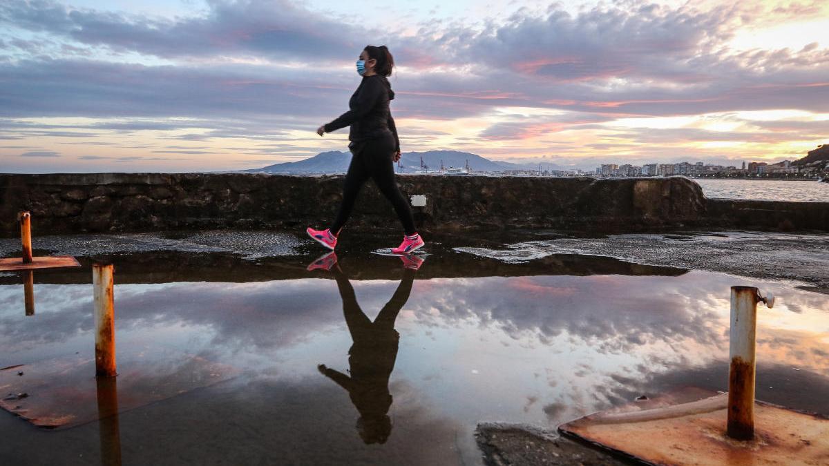 Una mujer, reflejada en un charco en el paseo marítimo