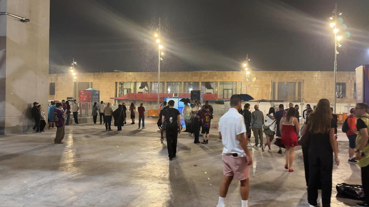 Aficionados del Barça y del Racing esperan en el campo a que baje la lluvia una hora después del partido