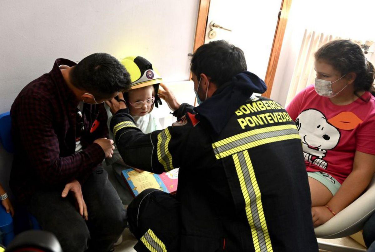 Uno de los bomberos prueba un casco a la pequeña Lucía. | // R.V.