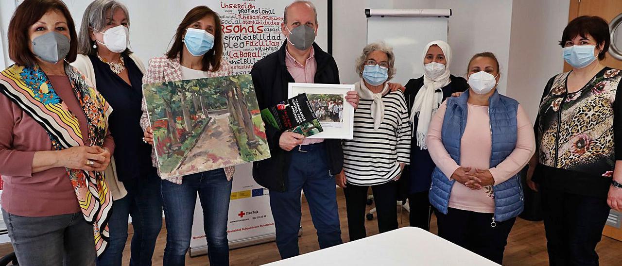 Sole Fernández, Berta López, Begoña González, con el cuadro de Favila, Favila, Fini Rodríguez, Fátima Isusi, Francisca Dos Santos y Maite Díaz, ayer, en las instalaciones avilesinas de la Cruz Roja.