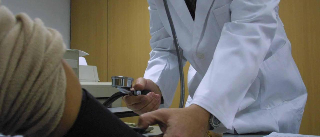 Un médico mide la tensióna un paciente en la consulta. l.O.