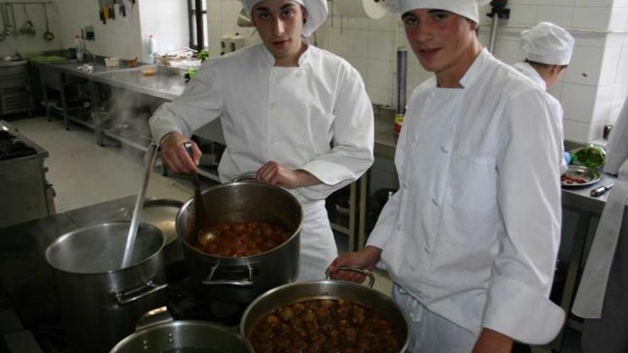 Los estudiantes Arturo Casado y Alberto Suárez, preparando cebollas rellenas y albóndigas de potro, ayer, en Tapia.