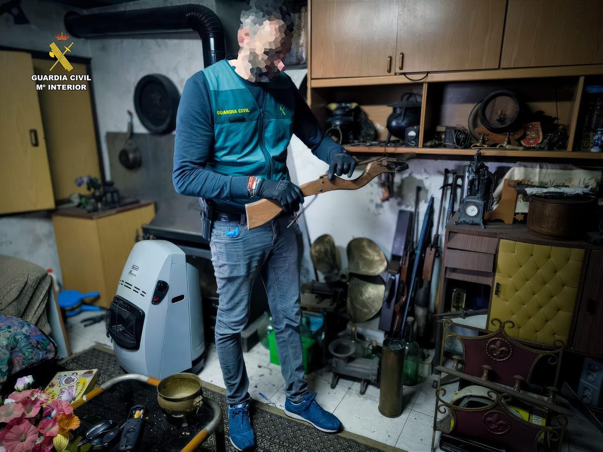 Un agente examinando una de las armas incautadas en el registro.