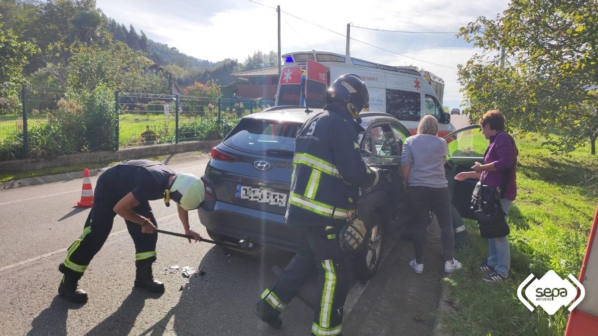 Bomberos junto al turismo accidentado.