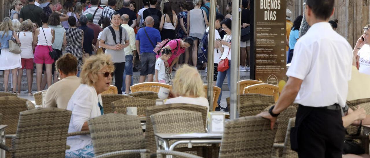 Un camarero permanece atento en una terraza de la Plaza de la Virgen. El sector servicios es uno de los protagonistas del mercado laboral valenciano.
