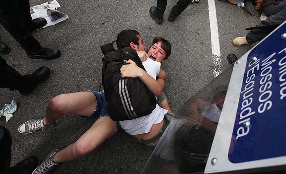 Una parella es protegeix a terra dels possibles cops dels Mossos d’Esquadra que han intentat desallotjar la plaça de Catalunya aquest divendres.