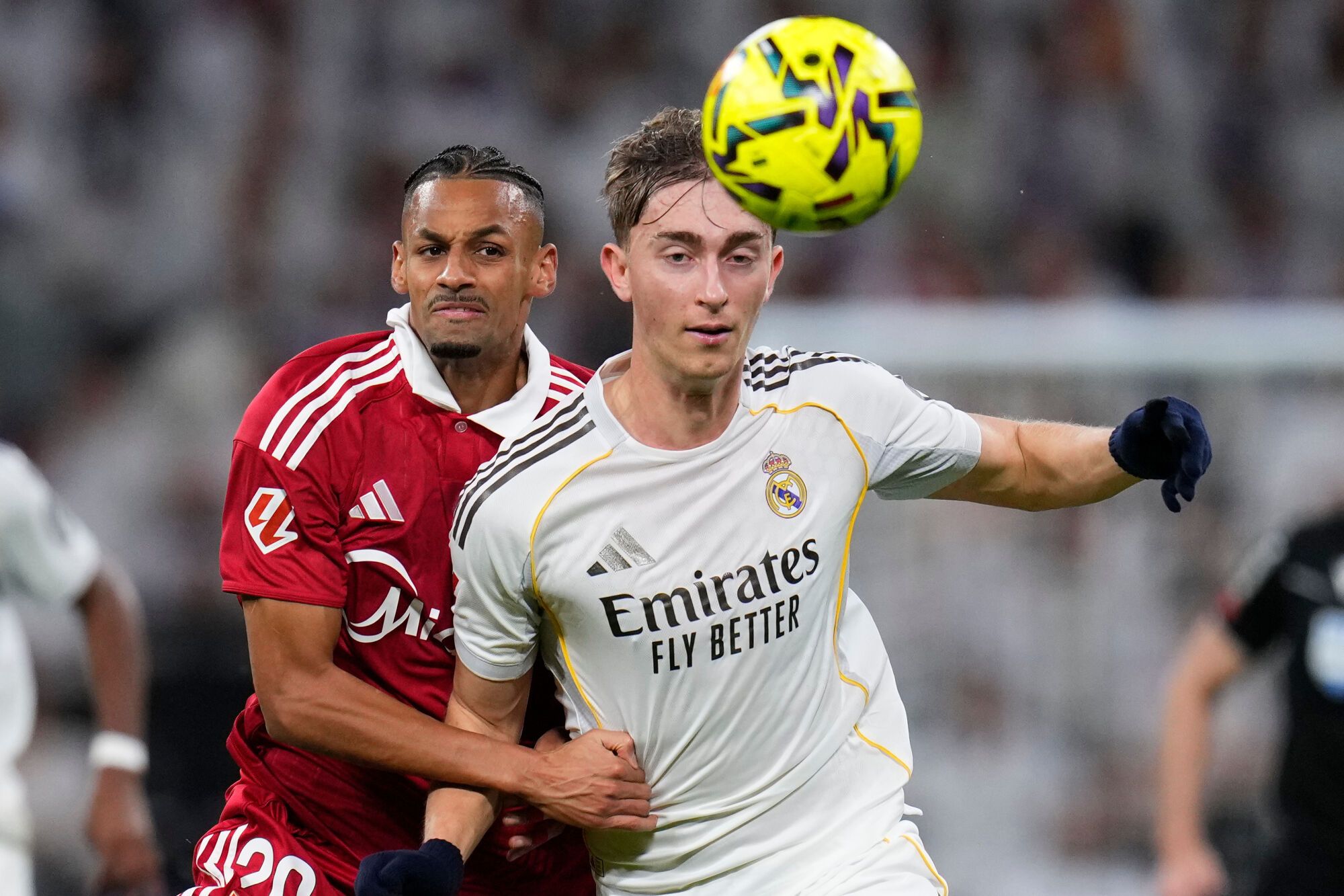 Real Madrid's Dean Huijsen, right holds of the challenge of Sevilla's Djibril Sow during the Spanish La Liga soccer match between Real Madrid and Sevilla in Madrid, Spain, Saturday, Dec. 20, 2025. (AP Photo/Manu Fernandez). EDITORIAL USE ONLY/ONLY ITALY AND SPAIN