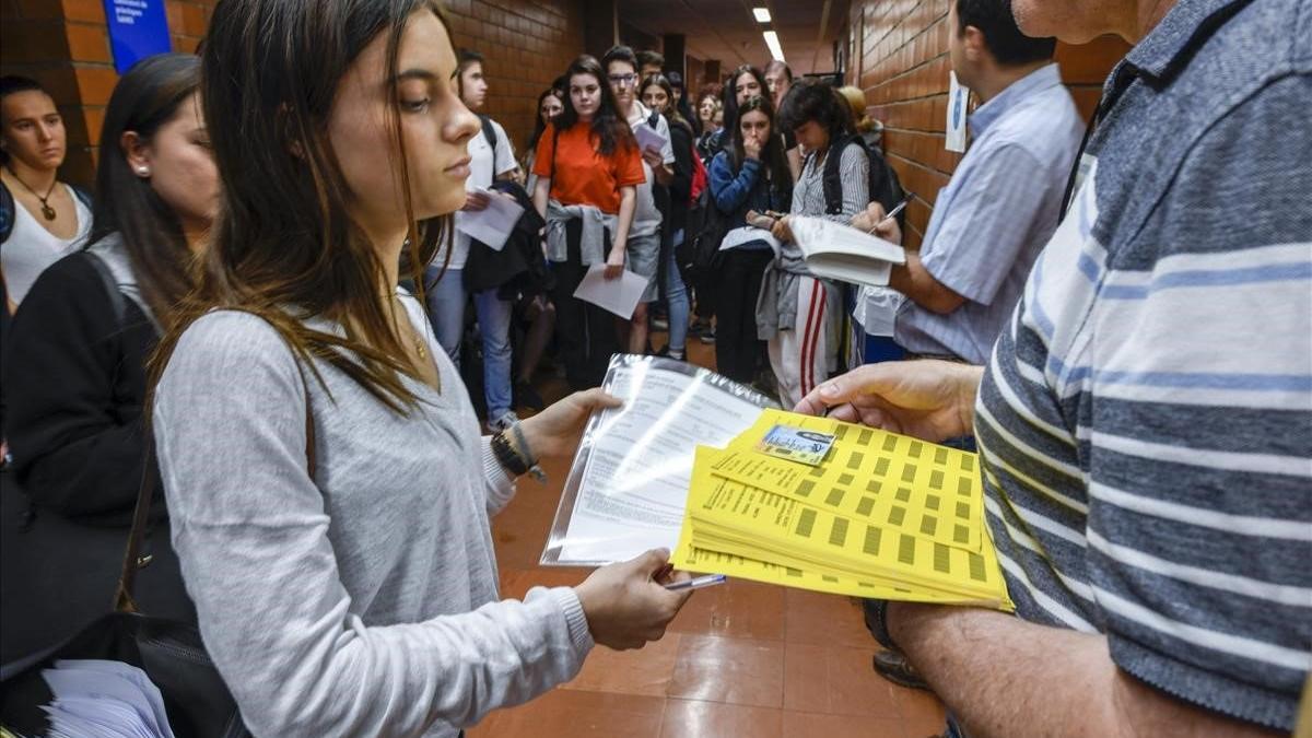 Una estudiante muestra su DNI, matrícula y etiquetas identificativas para acceder a uno de los exámenes de la selectividad