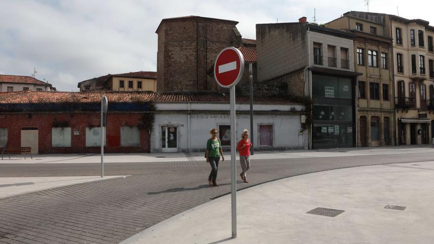 Arriba, edificios que se demolerán para sacar a la luz un tramo de la muralla medieval y el inmueble acristalado que se pretende rehabilitar como centro de interpretación.  A la derecha, el arqueólogo          Alejandro García ante el otro tramo de  muralla, en la zona para la que se proyecta una plaza a modo de     museo al aire libre sobre la            fortificación. |   Mara Villamuza