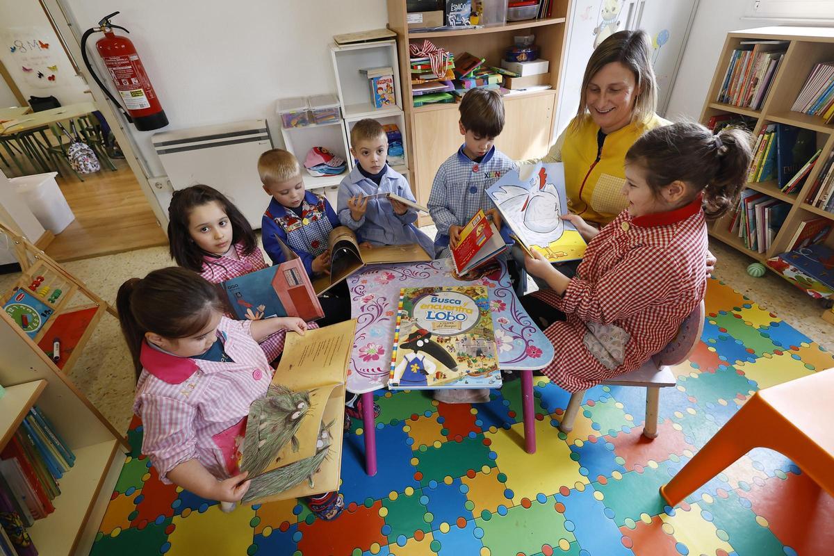 Los seis niños leen cuentos con su profesora.