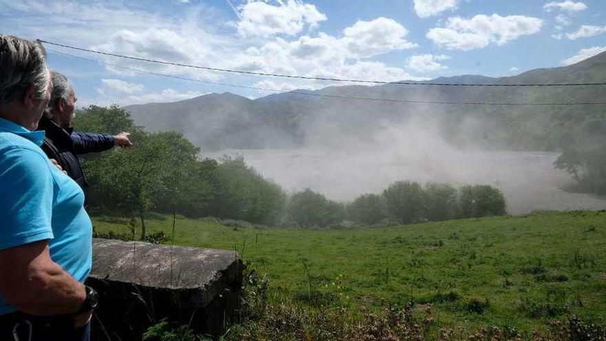 Dos vecinos señalan hacia un remolino de polvo generado por el viento en la escombrera de Pumardongo.