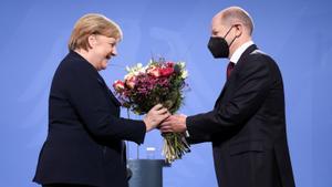 Olaf Sholz entrega a Angela Merkel un ramo de flores al tomarle el relevo en la cancillería alemana, en diciembre de 2021.