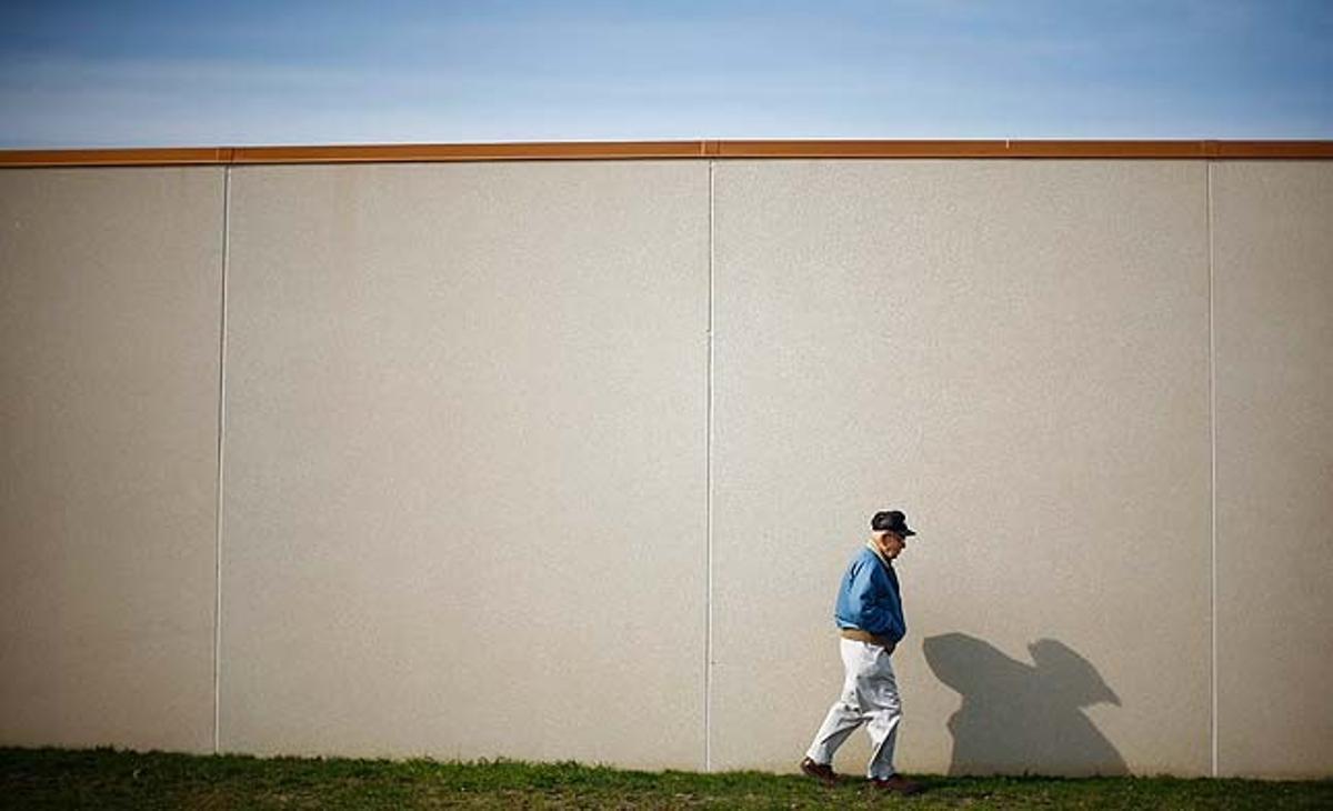 Un home camina davant d’un mur a prop d’una àrea inundada a Valley City, Dakota del Nord (Estats Units).